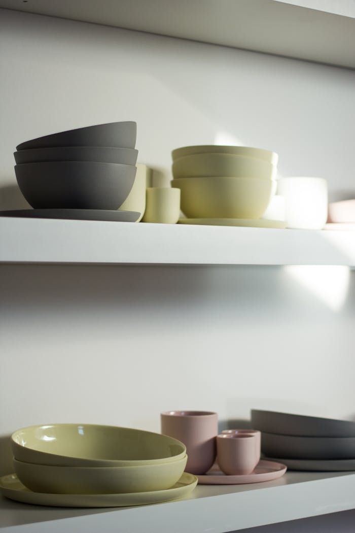 Stacked ceramic bowls and cups on minimalist shelves, showcasing kitchen organization.